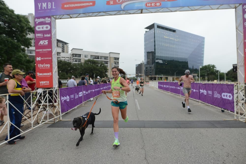 A person and their dog cross the finish line.
