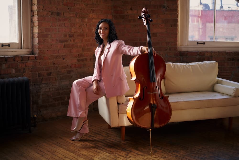Anita Graef sits on a couch with her cello. 