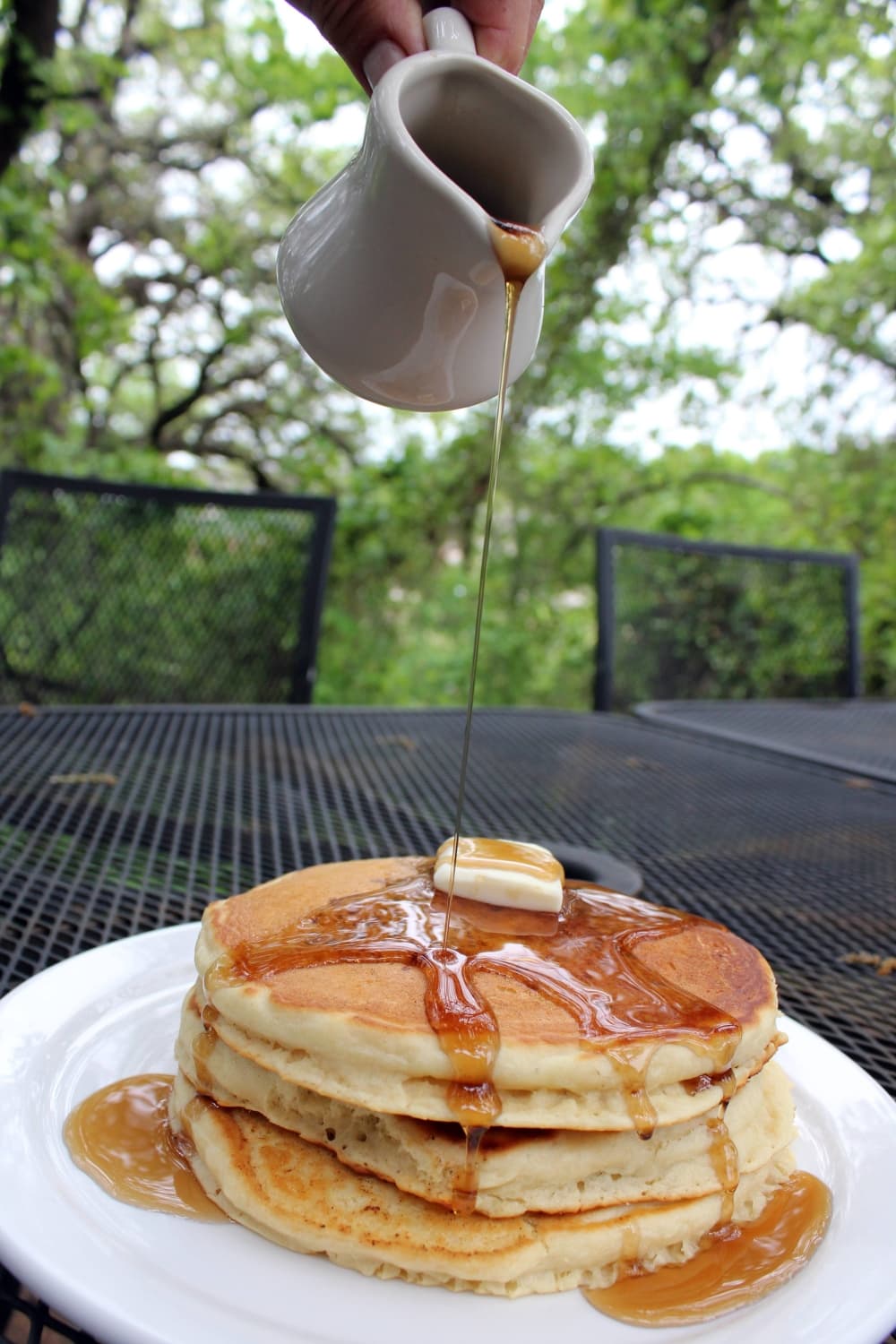 Pancakes with syrup being poured on them. 