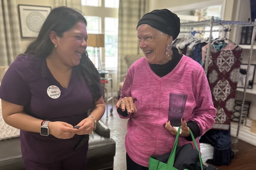 A woman shows off her ring and smiles with the caregiver.