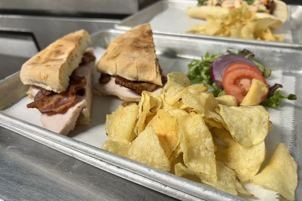 A sandwich on a tray is shown with chips.