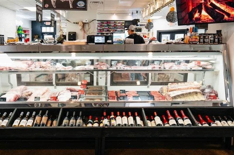 Bottles of wine on a shelf beneath a meat counter