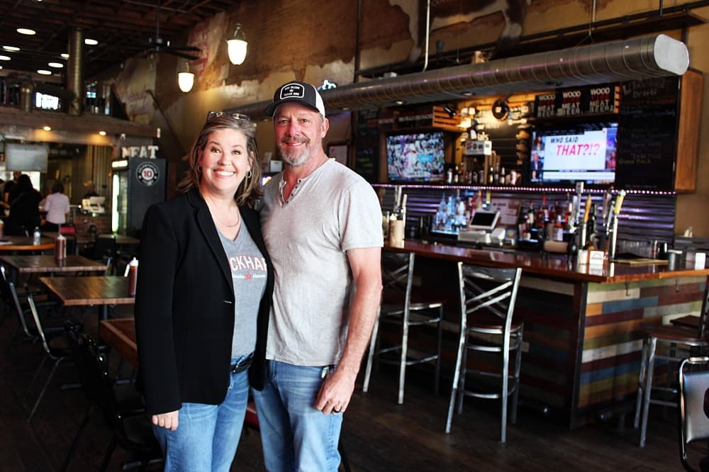 Female and male standing in a restaurant.