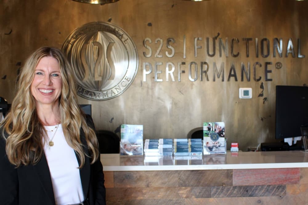 Female standing in front of a counter with S2S Functional Performance signage on the wall.