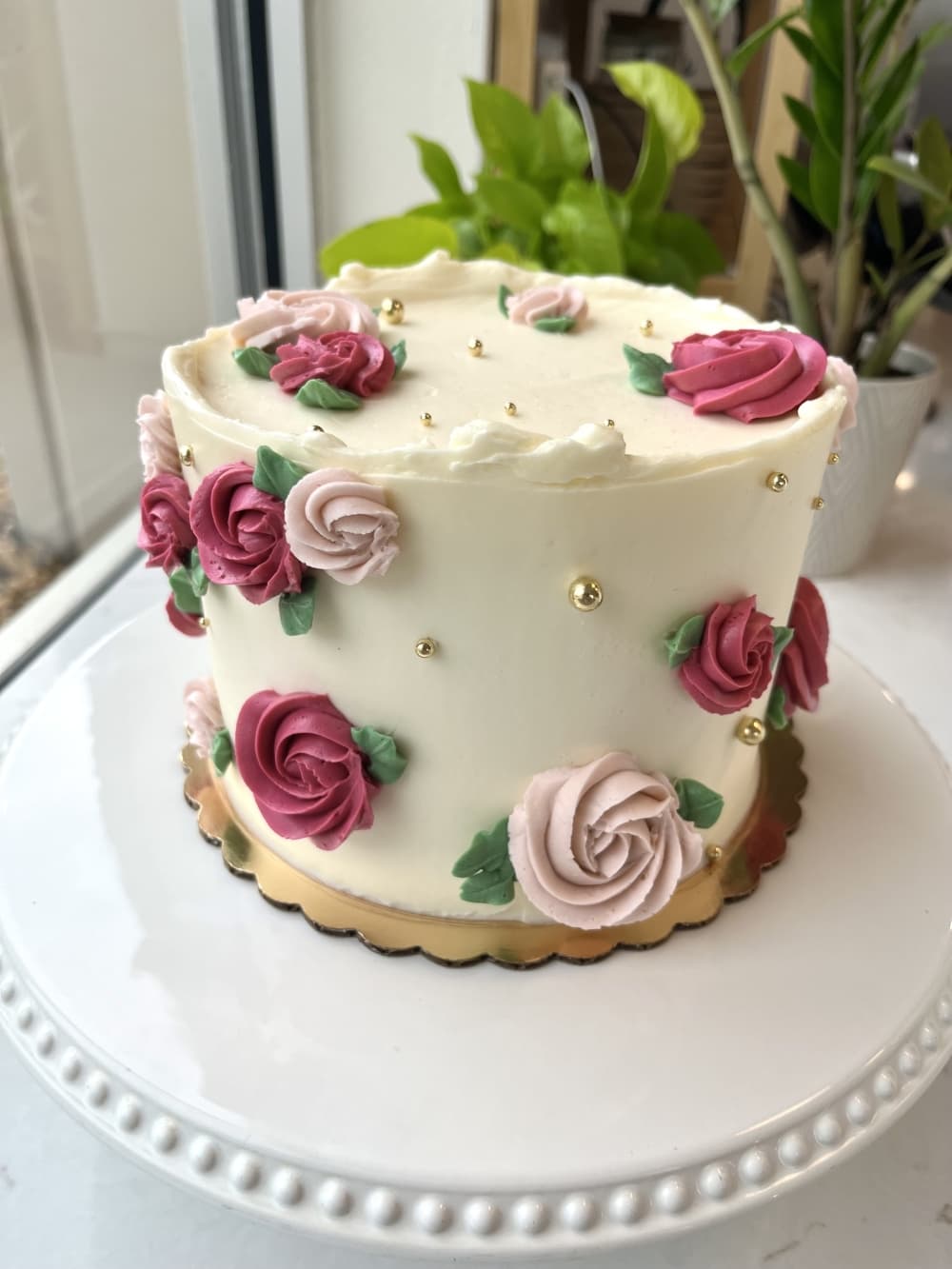 Layered cake with white frosting, decorated with roses. 