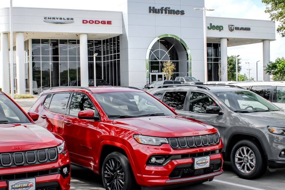 Cars in front of a dealership with Huffines Chrysler, Jeep, Dodge, Ram signage. 