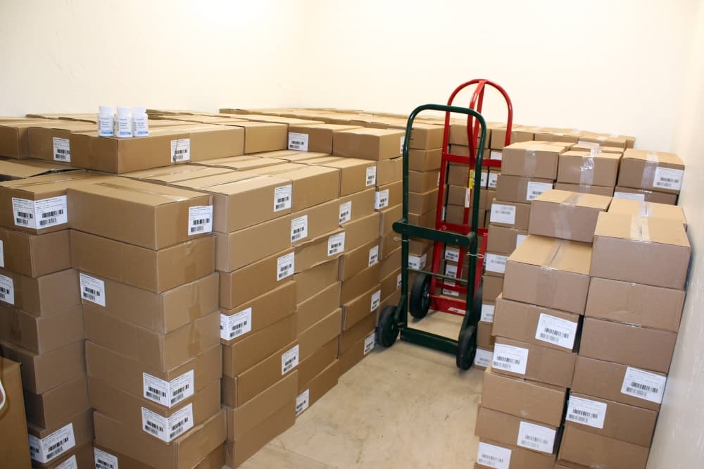 Boxes stacked in a room with hand carts. 