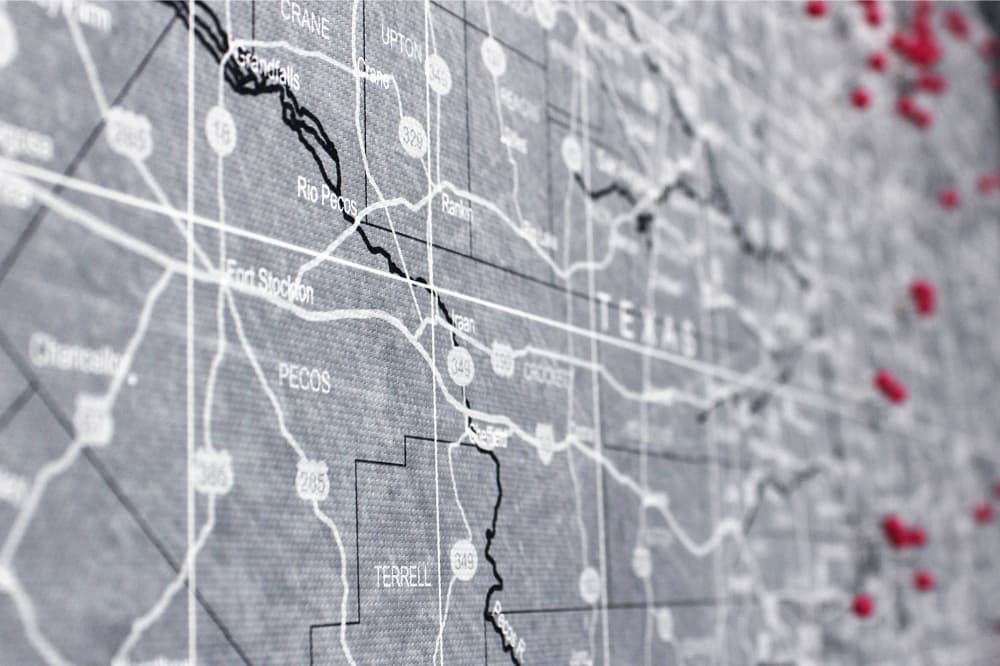 Close up of Texas map with red pins marking certain cities. 