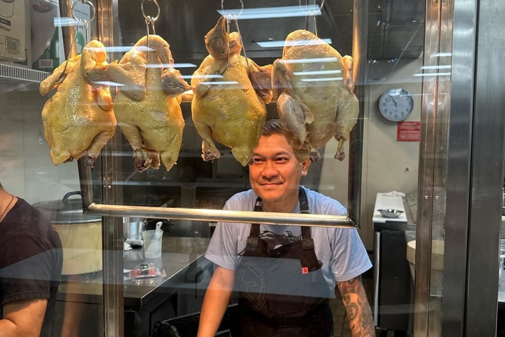 The owner smiles and looks at roasting chickens.