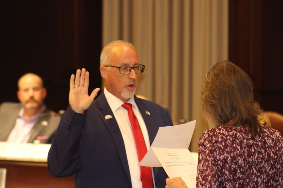 Picture of a man taking an oath at a meeting.
