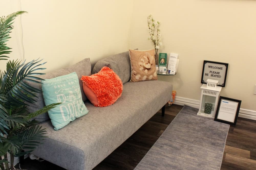Room with gray couch, salmon and light teal pillows. 