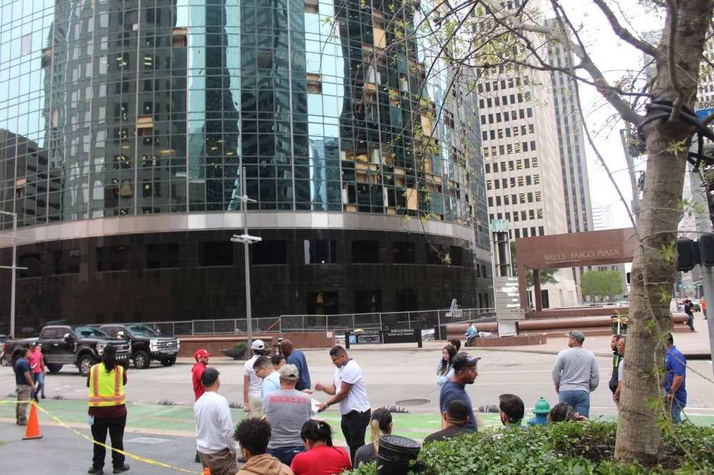 A crowd congregates near the Wells Fargo Plaza in Downtown Houston, where winds blew out dozens of windows of the 71-story building. (Shawn Arrajj/Community Impact)