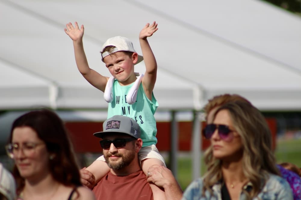 A child dances on his father's shoulders