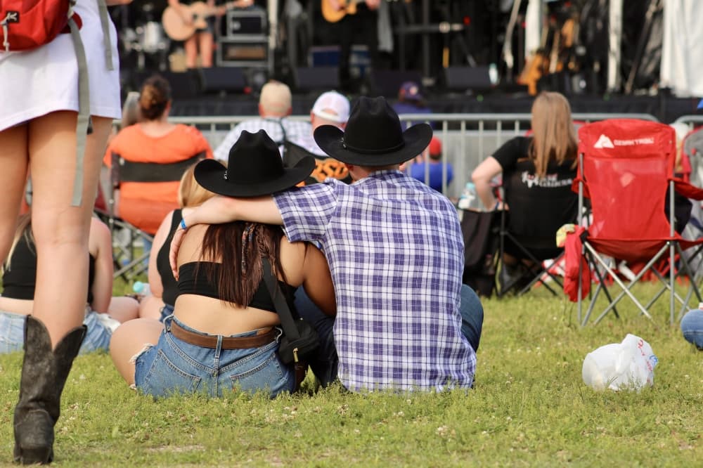 A couple sits on the lawn at a show