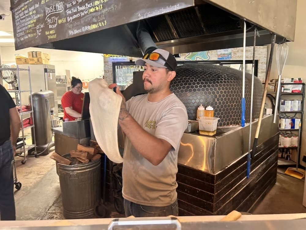 Image shows Chef Keanu Ledesma tossing pizza dough.