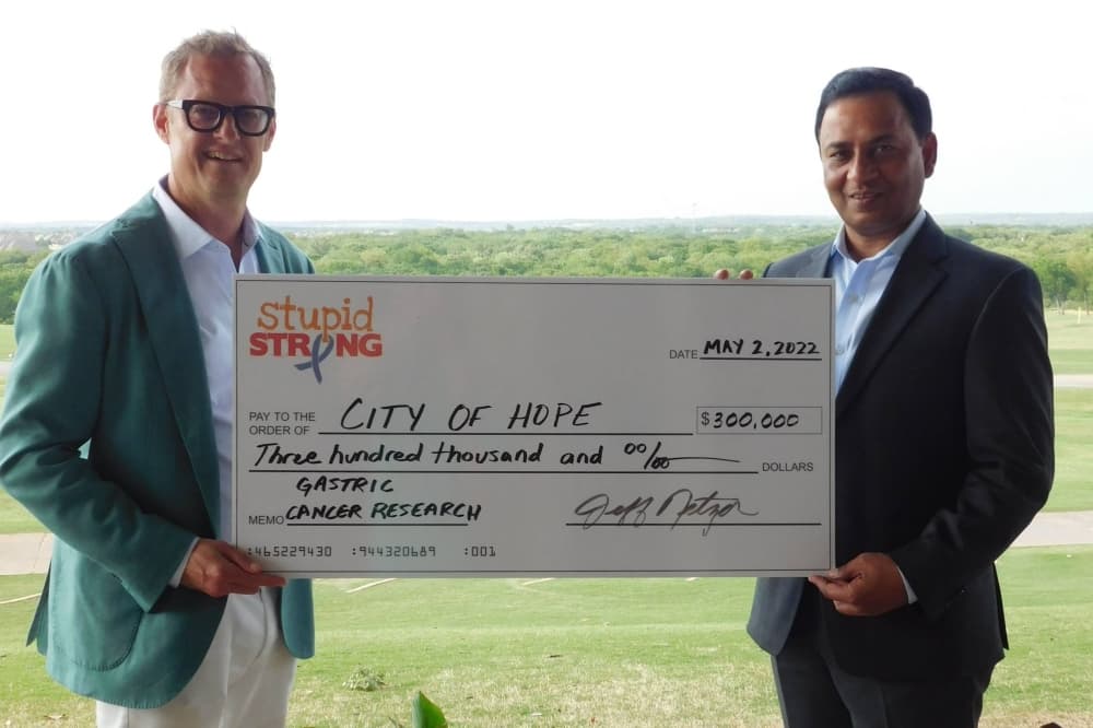 Two males holding an oversized check for the amount of $300,000. 