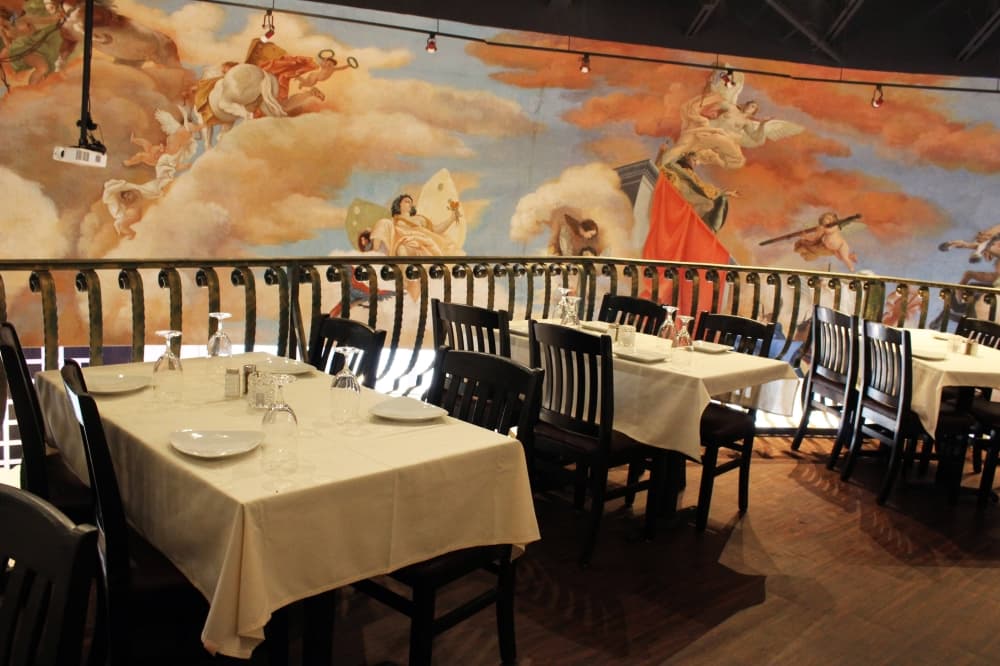 Tables with white cloth tablecloths with mural in background.