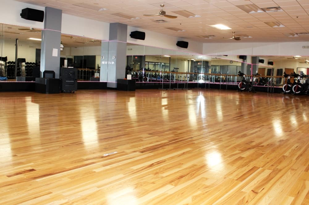 Wood dance floor lined with mirrors and stationary bikes. 