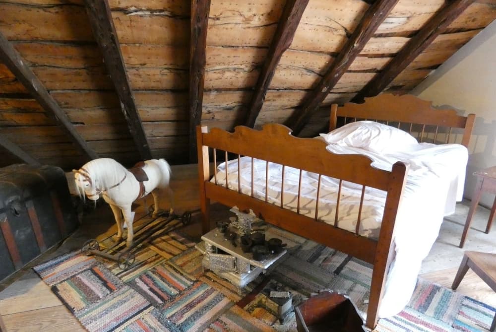 Image shows a child's bed in the attic of the Breustedt House.
