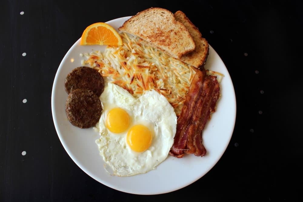 Eggs with bacon, sausage, hash browns and bread. 