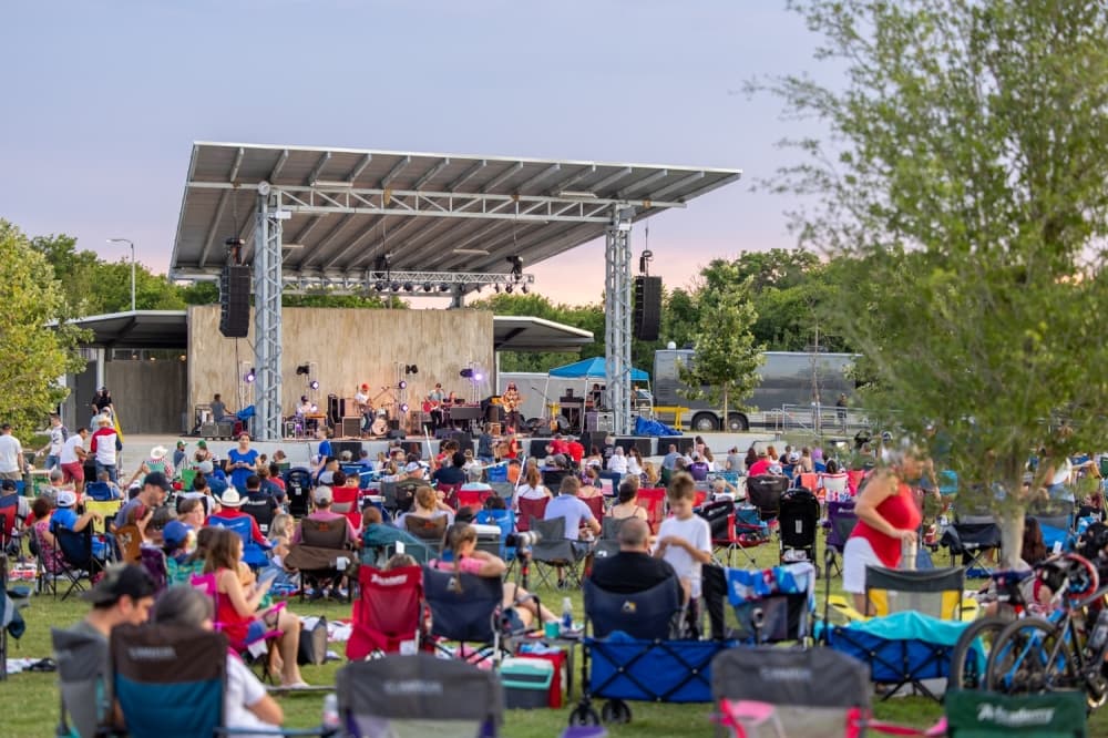 An image of a crowd sitting on the Buda Amphitheater lawn watching a live music performance. 