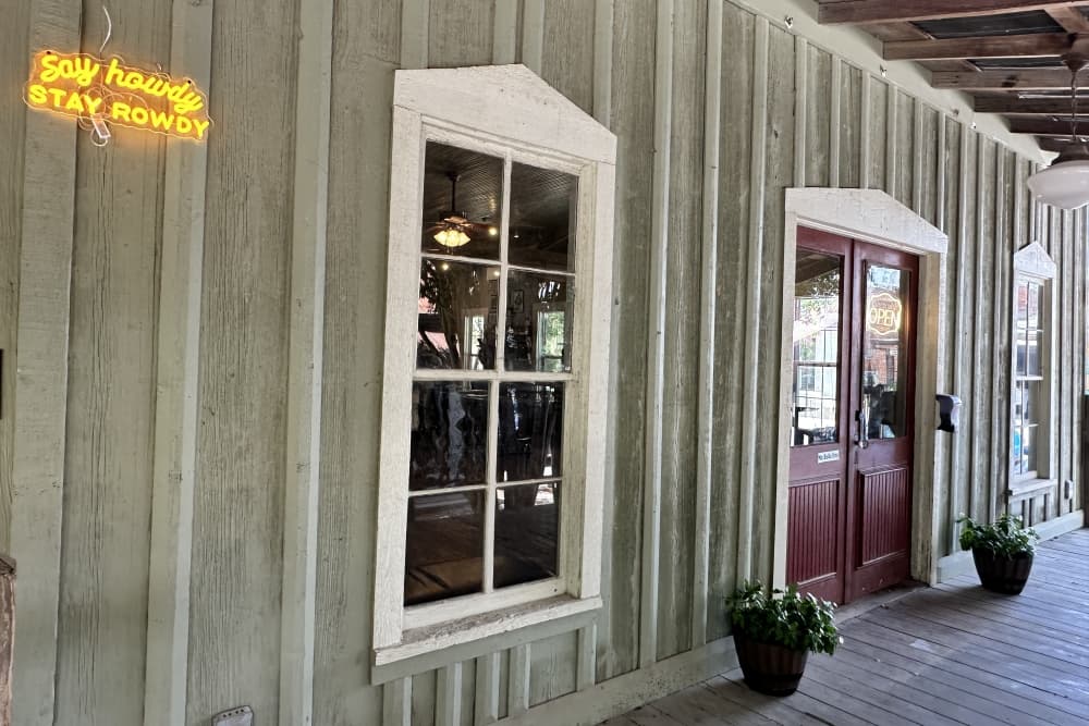 The front door is shown with a neon sign that reads, "Say Howdy, Stay Rowdy."