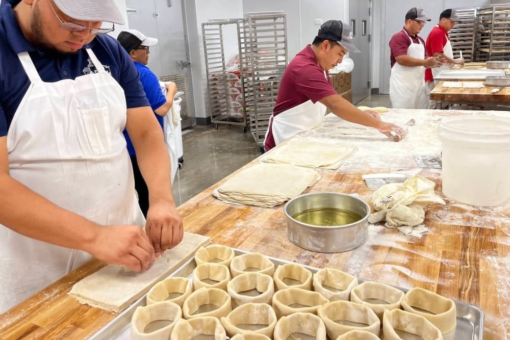 A photo of bakers in a bakery making pastas.
