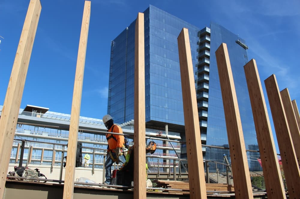 Construction worker walks behind planks of wood at Kaleidoscope Park