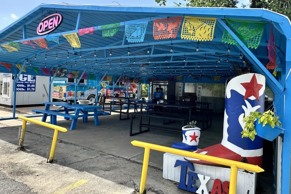 An exterior shot of the covered, blue-colored dining area next to the truck is shown with brightly colored decorations.