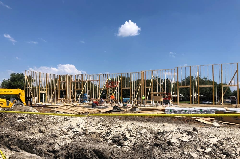 Construction site with frame of one wall of building. 