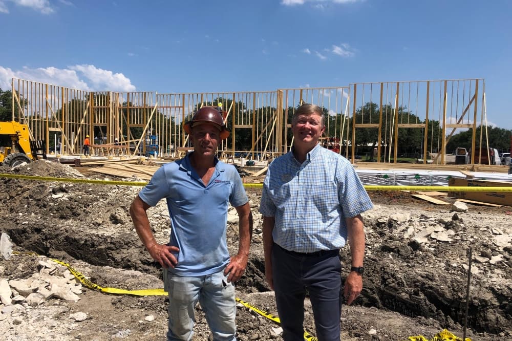 Two males standing at a construction site. 