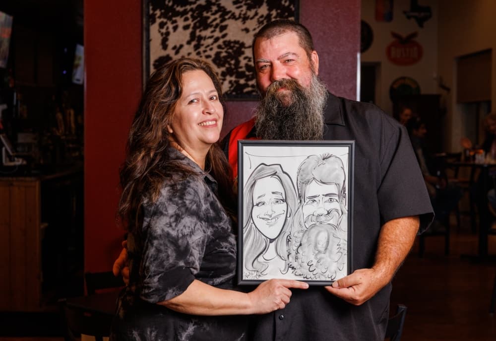 The owners hold up a caricature and smile.