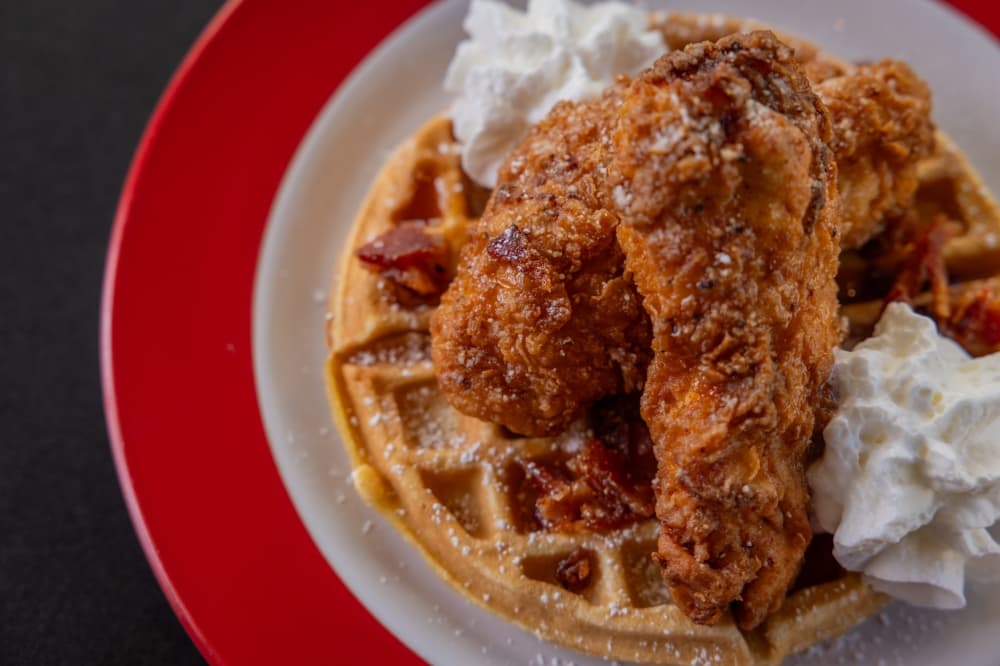Chicken and waffles are shown on a red charger plate.