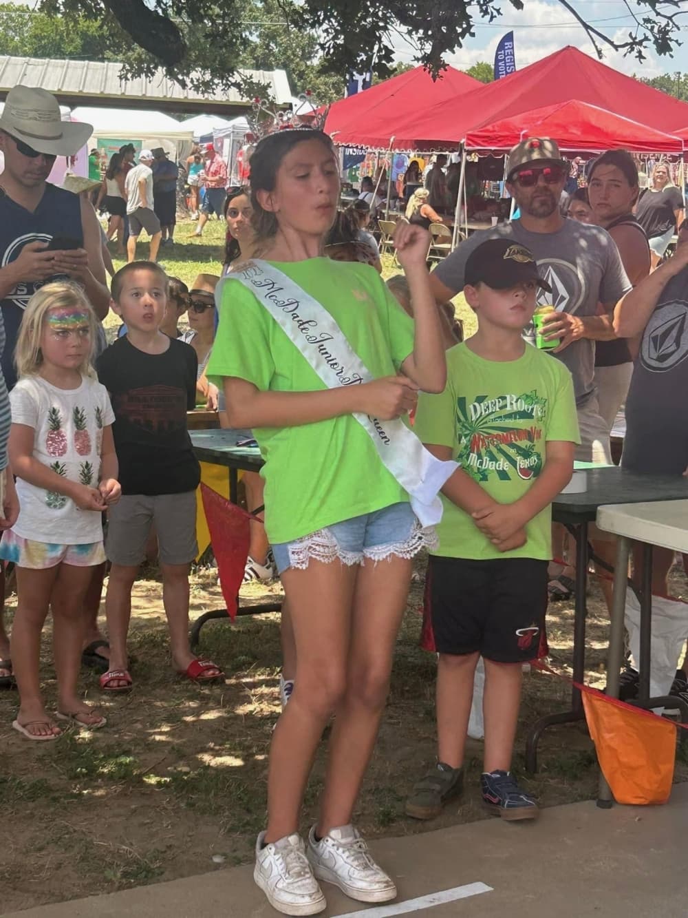 A child spits a watermelon seed as a crowd watches.