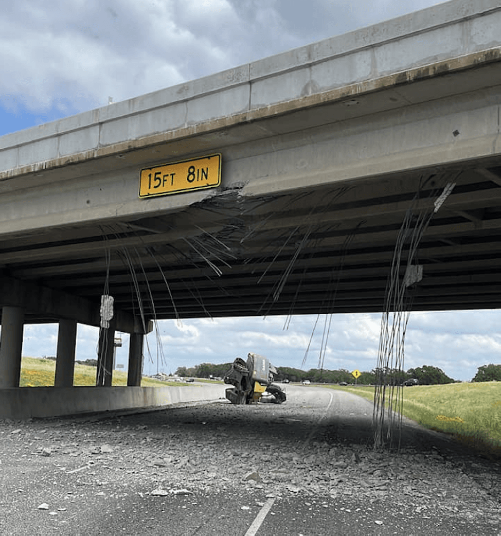 The underside of the bridge is shown damaged with the excavator on its side int he background.