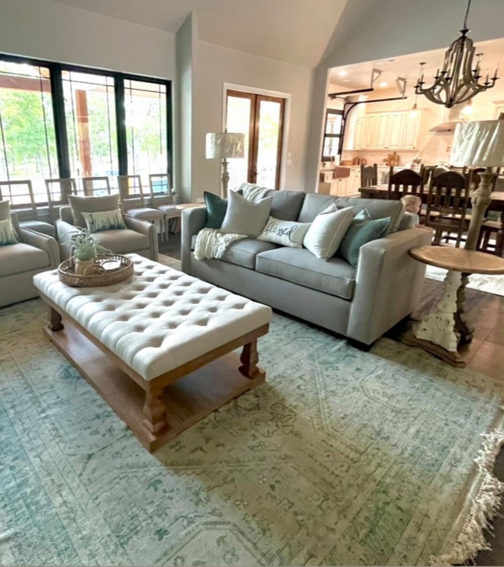 A living area is shown with a rug, couch, pillows and blanket.