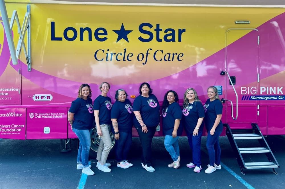 A group of workers pose in front of the bus.