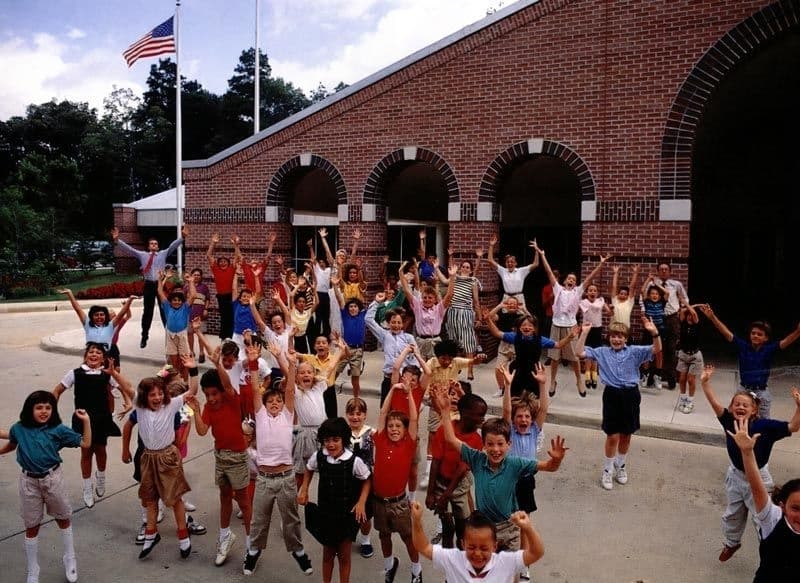 Kids jumping up in front of a school building