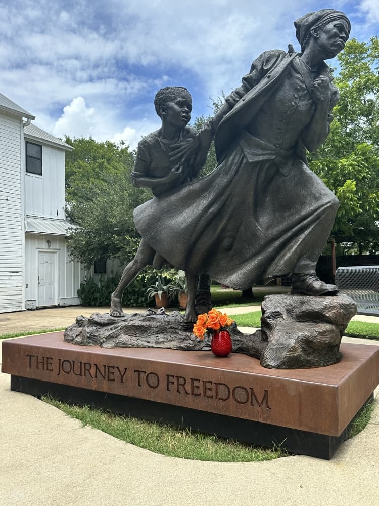 The statue is shown from the front side, with Harriet Tubman holding the hand of a small child and leading them forward.