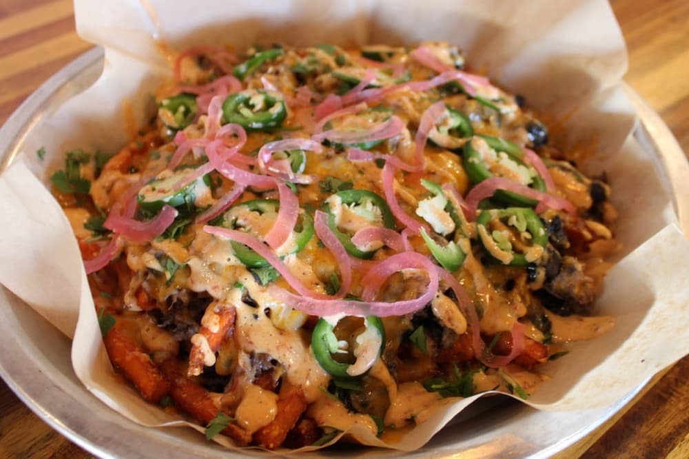 The loaded sweet potato fries ($12) are topped with housemade pulled pork, black beans, colby jack cheese, pickled onion and cilantro. (Sarah Hernandez/Community Impact)