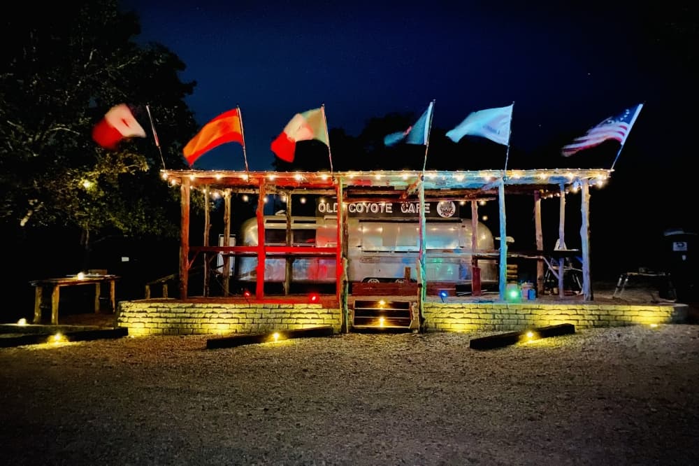 The front exterior at night with lights and flags.