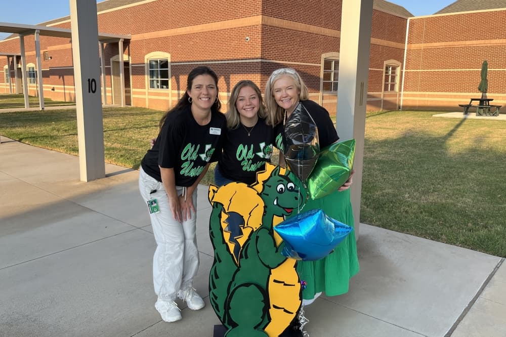 Teachers pose in front of dragon mascot