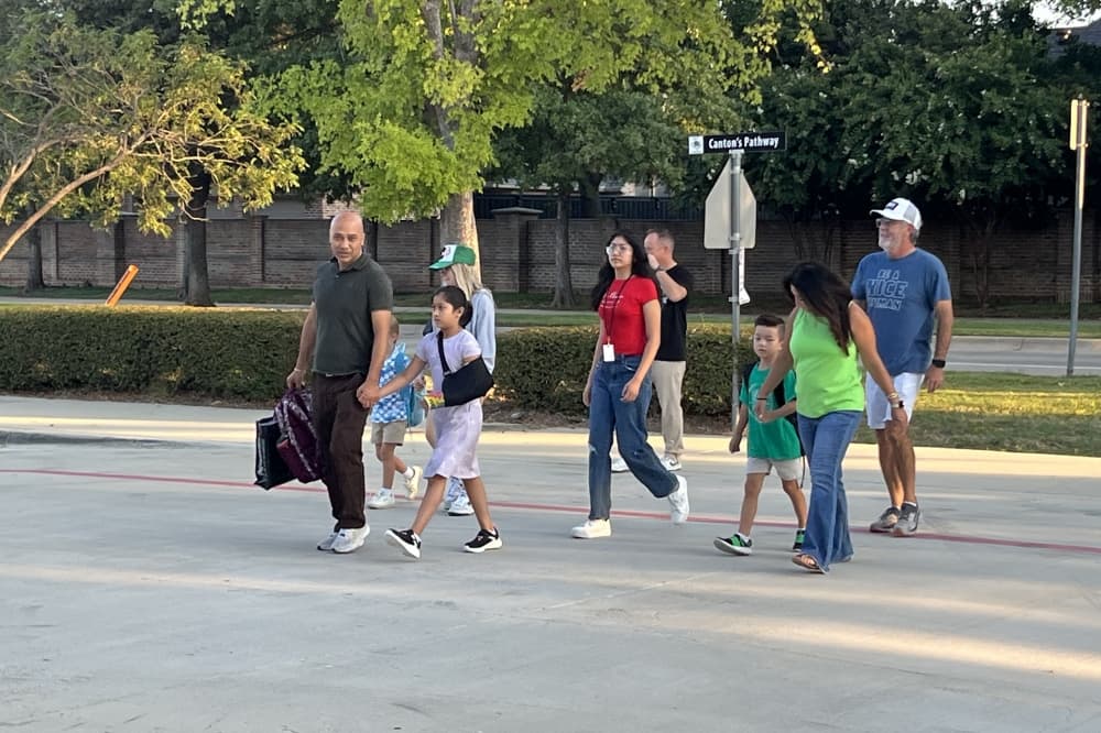 Students and parents walking in parking lot toward school