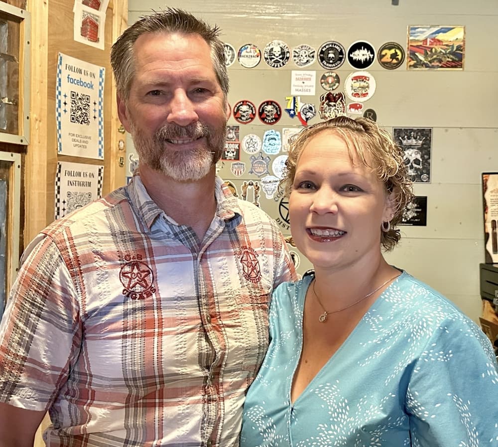 The owners smile for a photo inside the walk-in humidor.