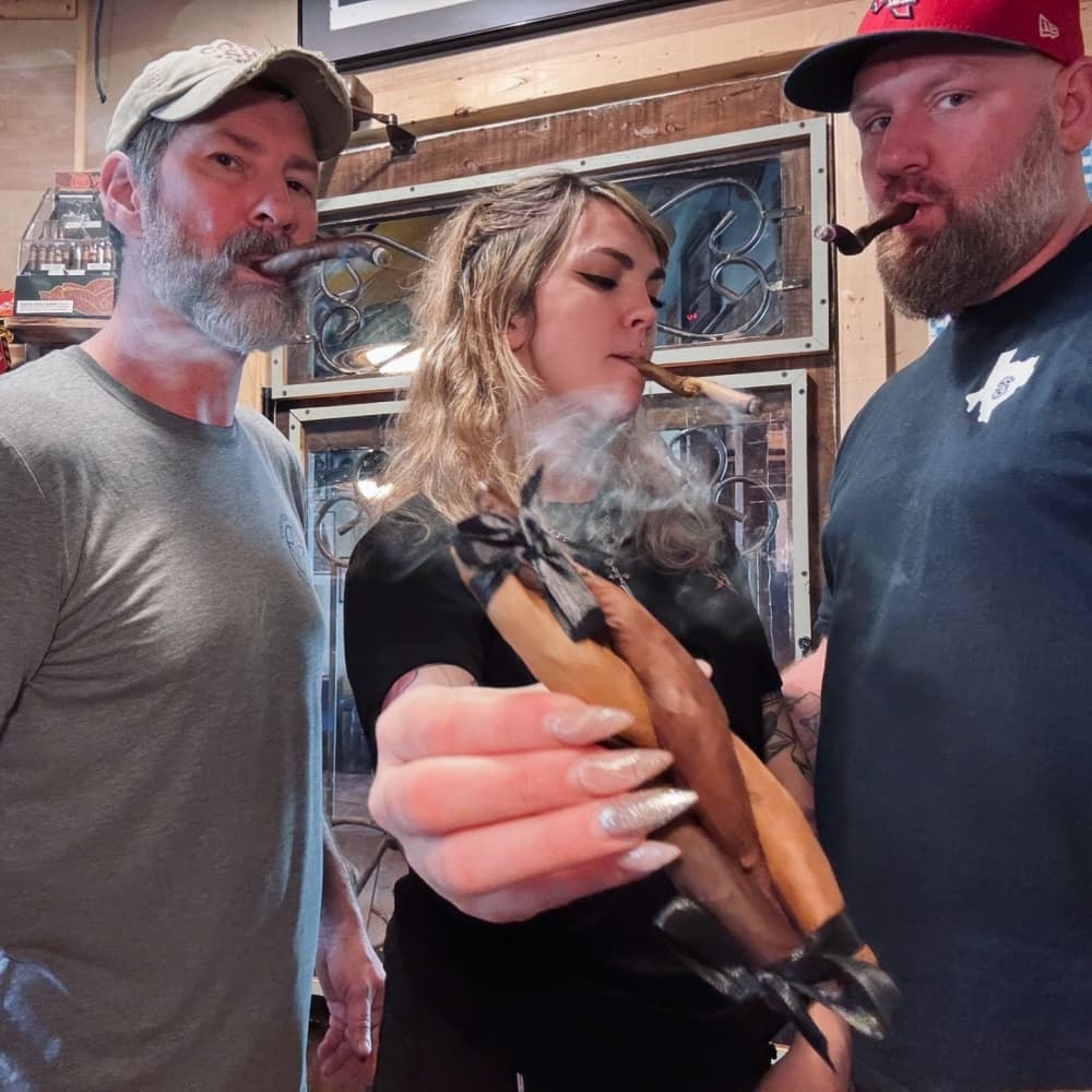 Three people pose for a photo holding the Turducken cigar.