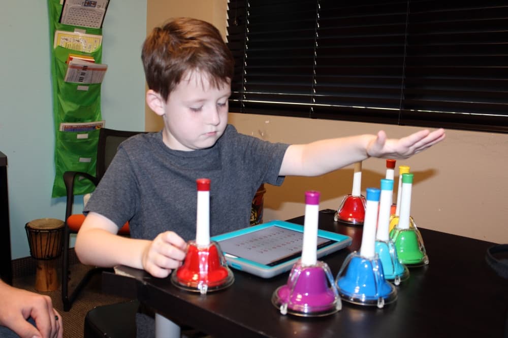 Boy playing multi-colored bells. 