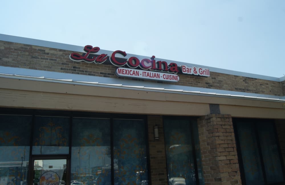 A store has a sign outside reading, 'La Cocina Bar & Grill.' 