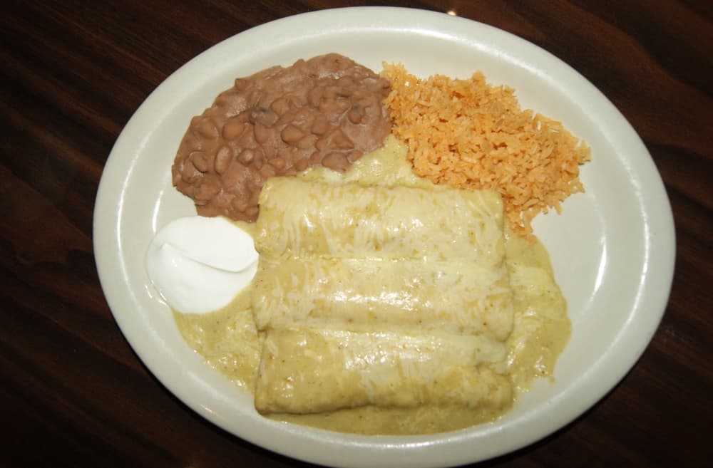 Three enchiladas served with rice, beans and sour cream. 