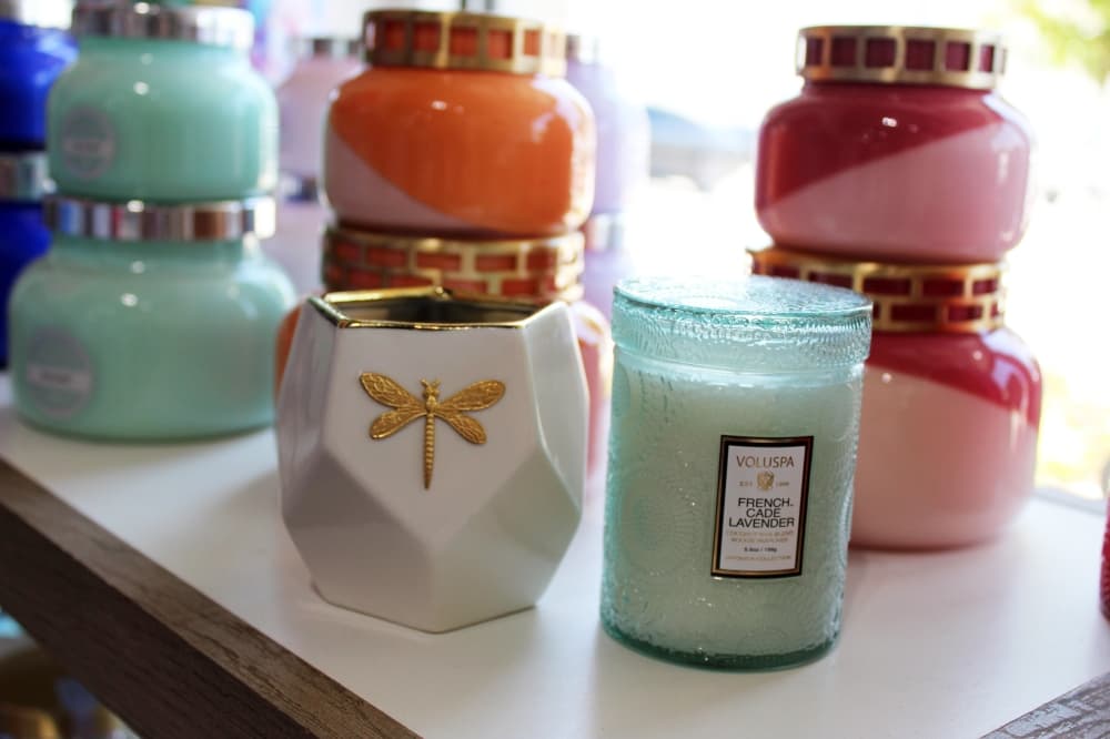 Various types and colors of candles in glass containers. 