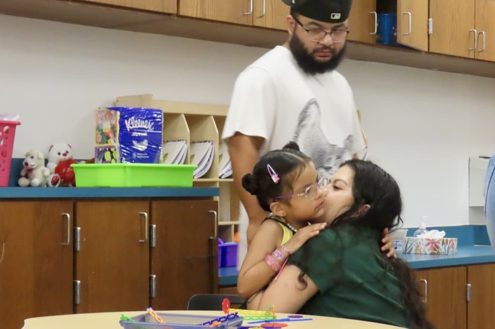 Parents hug their child goodbye as they leave on the first day back to class Aug. 14. (Jonathan Perriello/Community Impact)